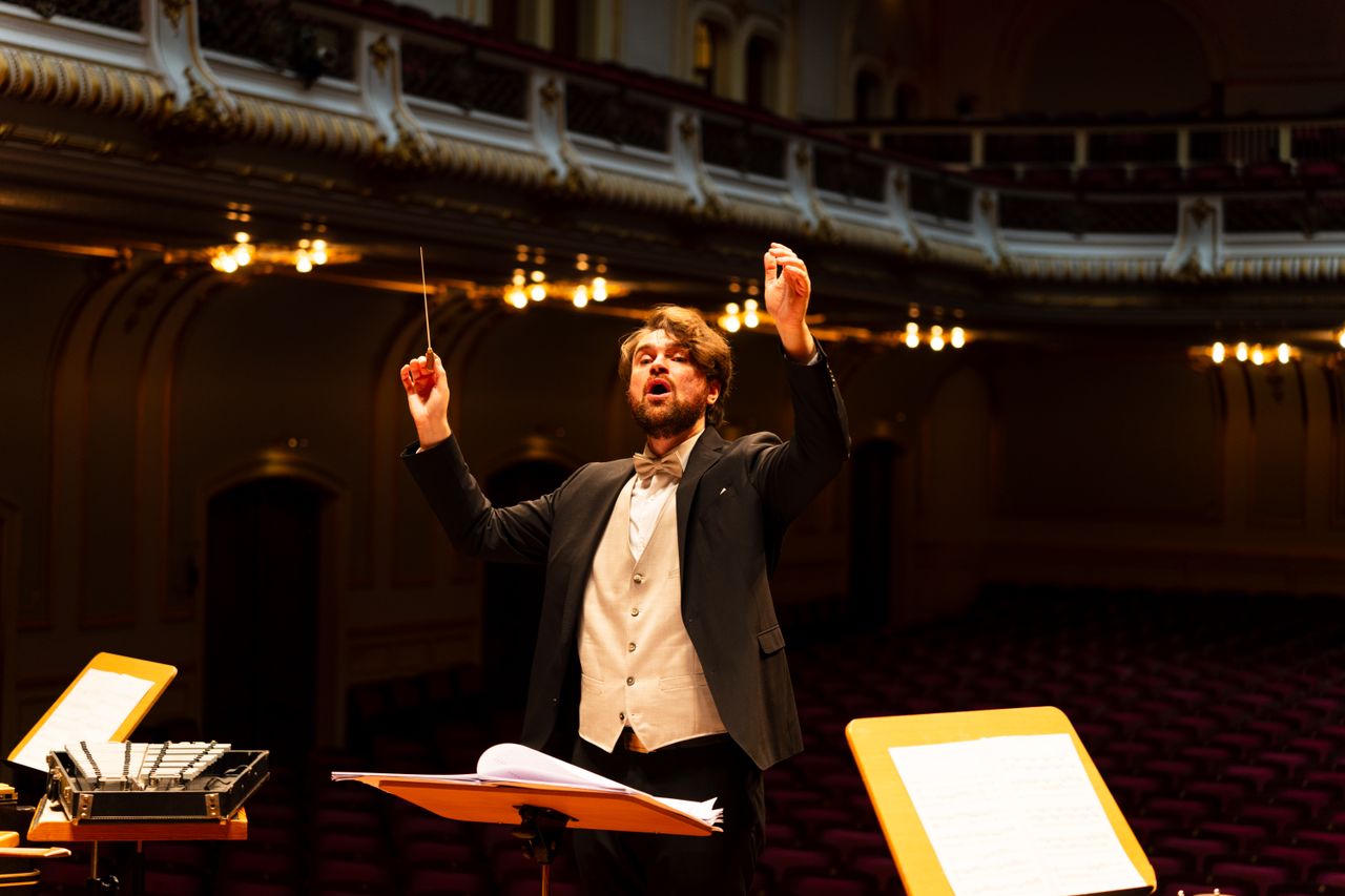 Mastering the First Impression: Your intriguing post title goes here Orchestra conductor passionately leading a performance in an elegant concert hall.