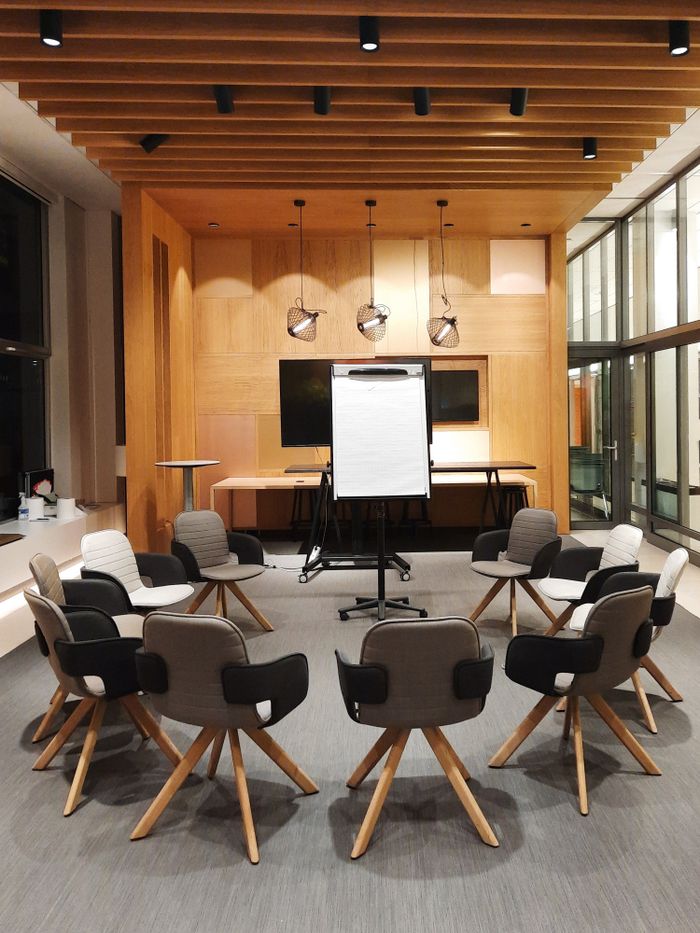 Home A modern conference room featuring circular seating and a flip chart, ideal for meetings and presentations.